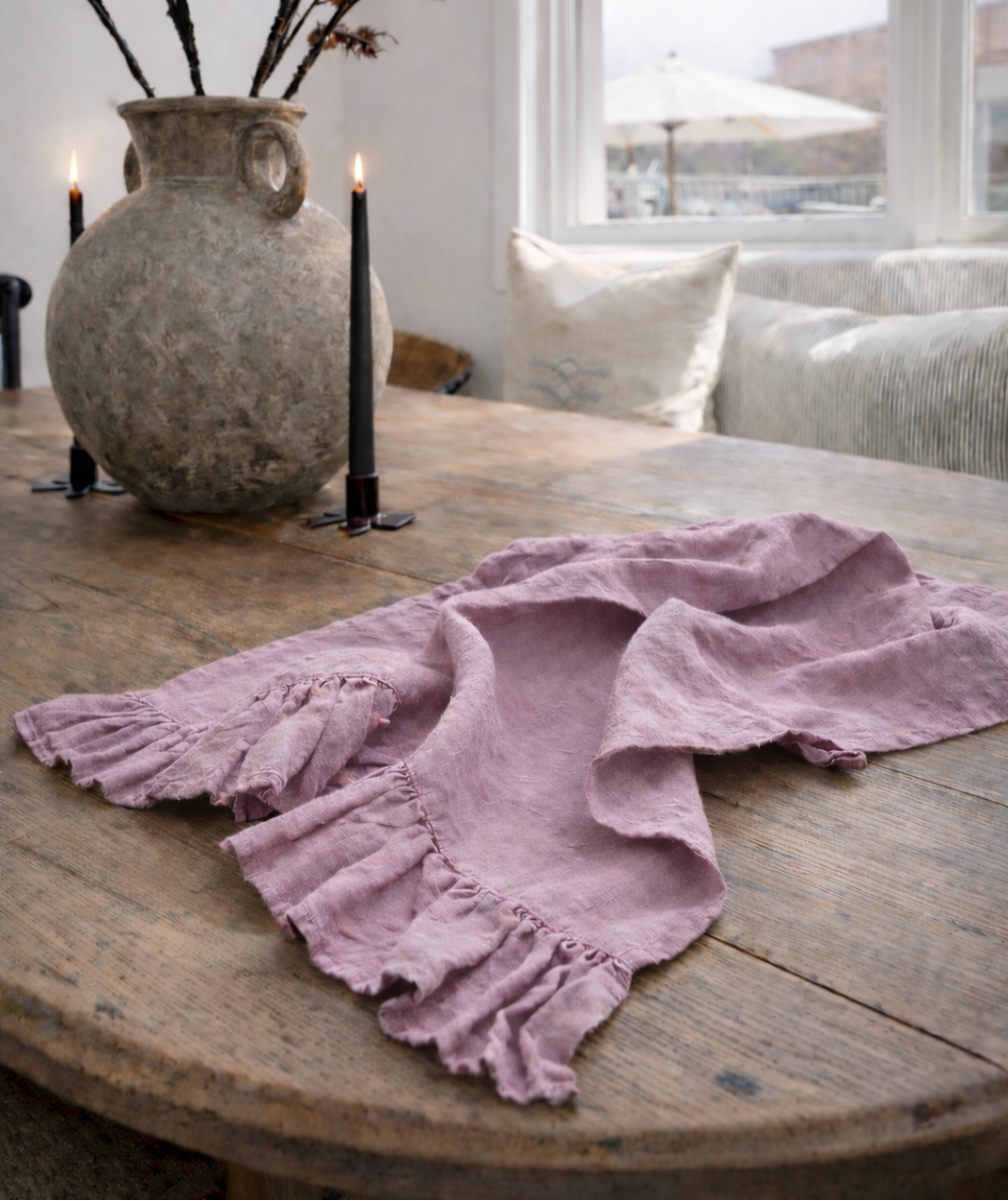 Saltbush Living lilac coloured Lisiére Linen Tea Towel with a frill on a wooden dining table next to candles and a vase