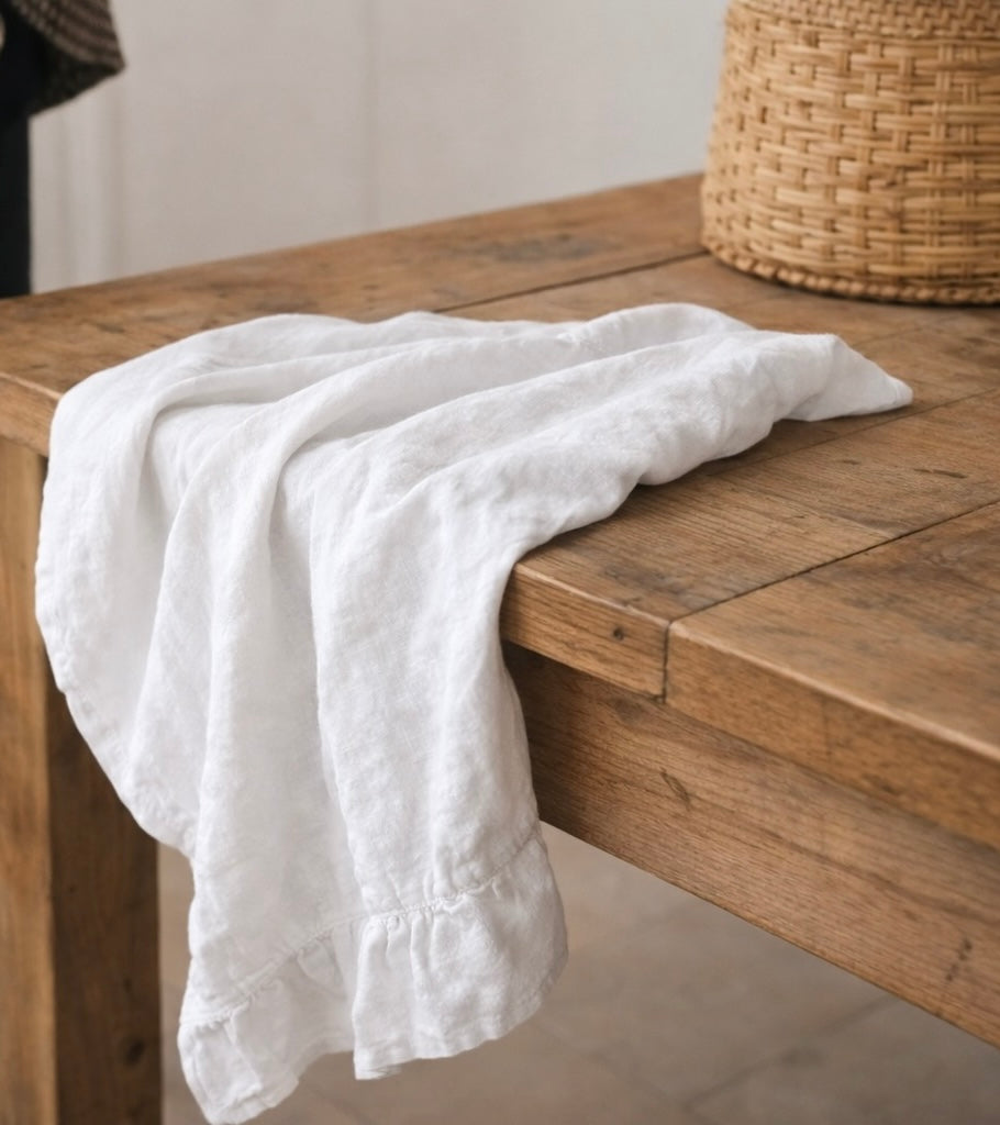 Saltbush Living white Lisiére french linen tea towel hanging from the side of a wooden table