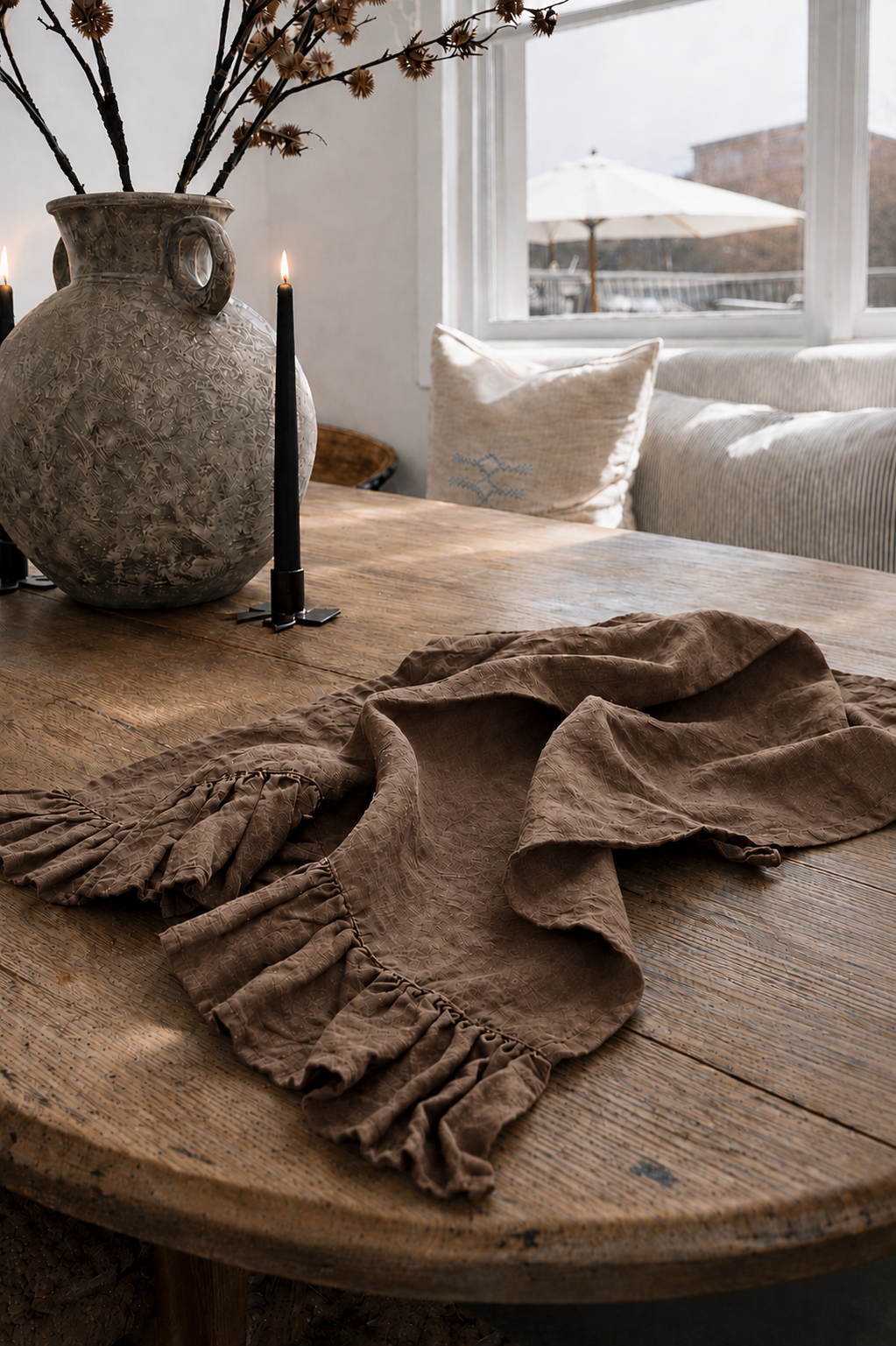 Saltbush Living chocolate coloured Lisiére Linen Tea Towel with a frill on a wooden dining table next to candles and a vase