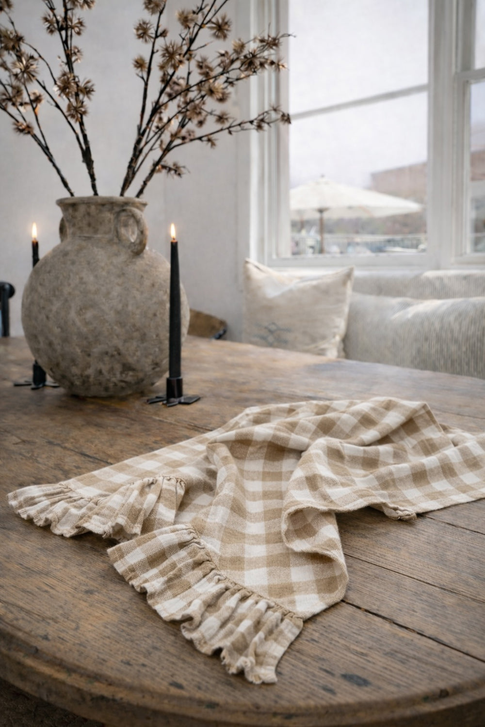 Saltbush Living gingham coloured Lisiére Linen Tea Towel with a frill on a wooden dining table next to candles and a vase