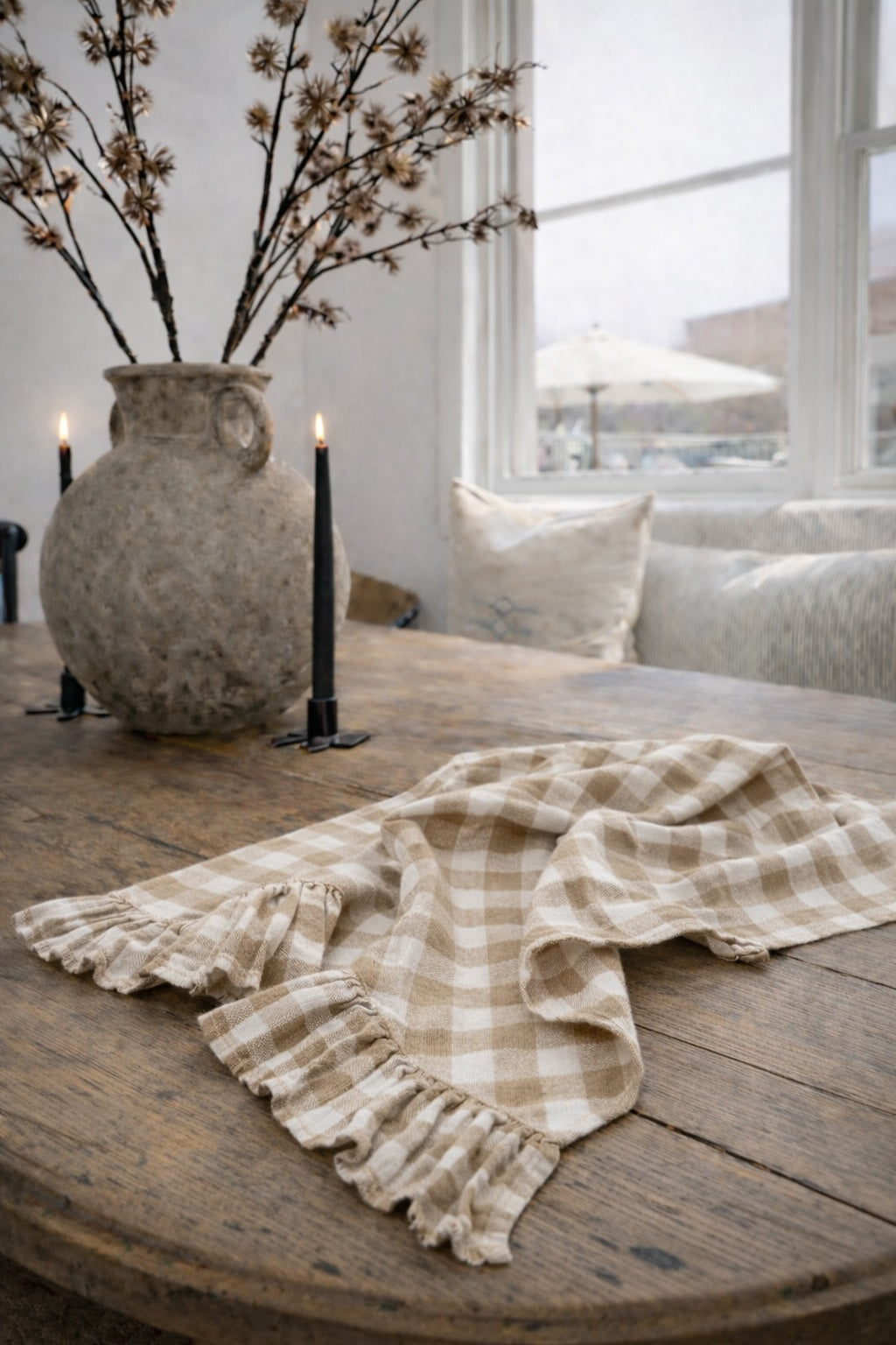 Saltbush Living gingham coloured Lisiére Linen Tea Towel with a frill on a wooden dining table next to candles and a vase